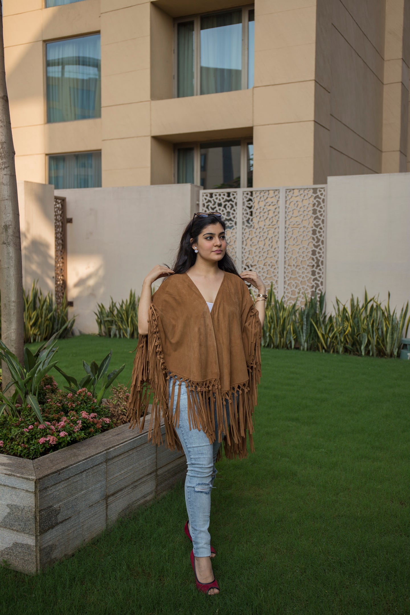 Our SUEDE LEATHER PONCHO with tussles in tan colour worn by a female model