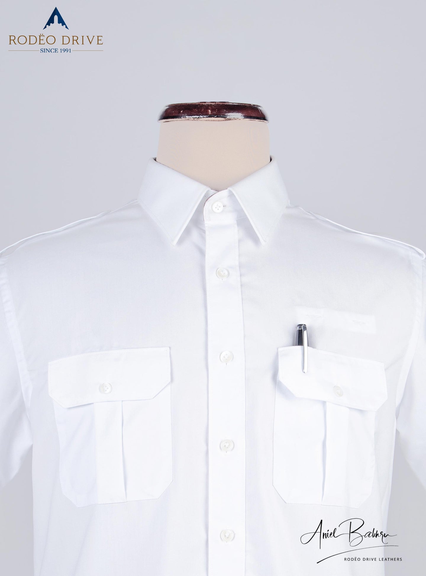 Close image of white Pilot Shirt. Shirt is buttoned. a pen tucked inside one pocket.